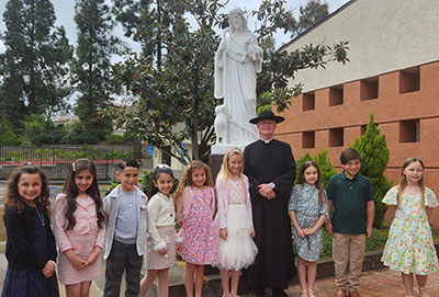 Pastor taking a photo with the children in front of the statue of Jesus