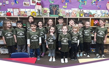 Group of happy preschool students wearing green t-shirts
