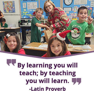 Photo of students with teacher in classroom with quote, By learning you will teach by teaching you will learn. - Latin Proverb