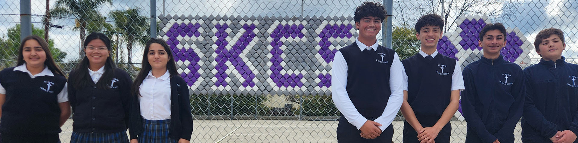 Happy students in front of SKCS letters on fence