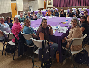 Teachers sitting around a table smiling at the camera